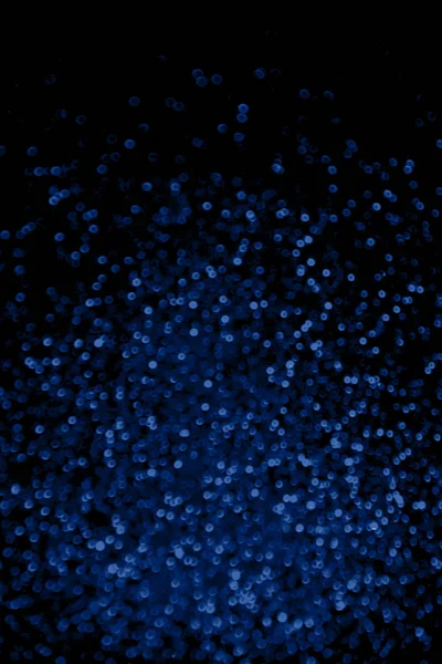 Abstrato azul brilho confete brilhos no fundo preto . — Fotografia de Stock
