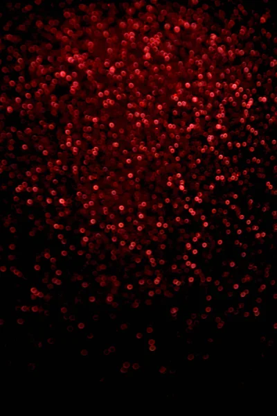 Confeti de purpurina roja abstracta borrosa brilla sobre fondo negro . — Foto de Stock