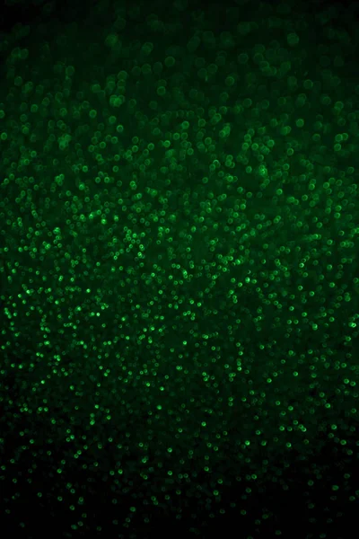 Confeti de purpurina verde abstracta borrosa brilla sobre fondo negro . — Foto de Stock