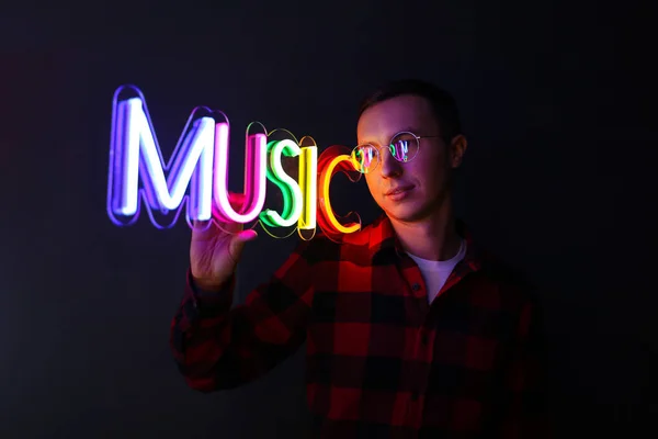 Homem bonito Hipster por sinais de néon. Sinal de neon multicolorido música . — Fotografia de Stock