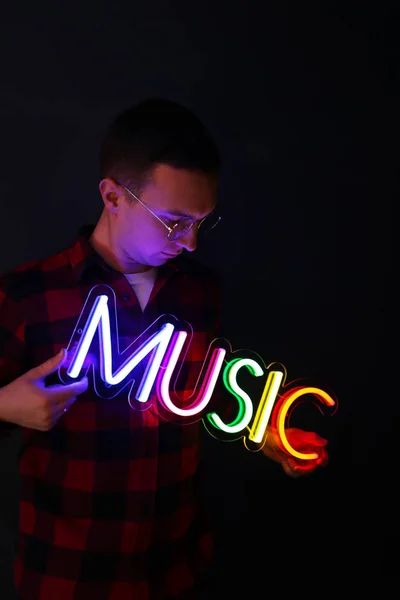 Hipster bel homme par des signes au néon. Multicolore néon signe musique . — Photo