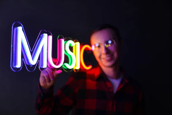 Hipster bel homme par des signes au néon. Multicolore néon signe musique . — Photo