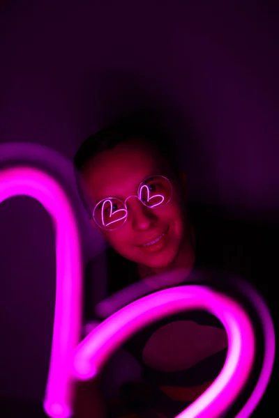 Valentijnsdag. Hipster knappe man met neon tekens. Neon teken roze hart. — Stockfoto