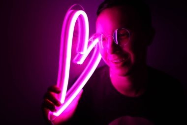Sevgililer Günü. Neon tabelalı hippi yakışıklı adam. Neon işareti pembe kalp.
