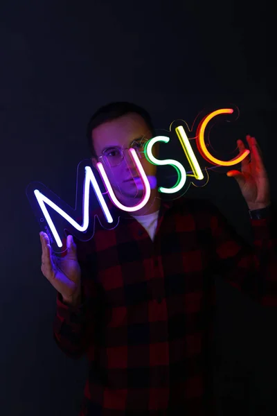 Homem bonito Hipster por sinais de néon. Sinal de neon multicolorido música . — Fotografia de Stock