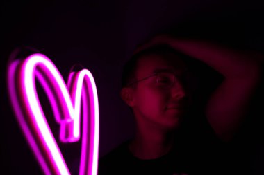 Sevgililer Günü. Neon tabelalı hippi yakışıklı adam. Neon işareti pembe kalp.