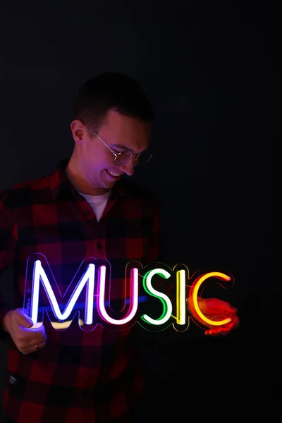 Hipster stilig man vid neon tecken. Flerfärgad neonskylt musik. — Stockfoto