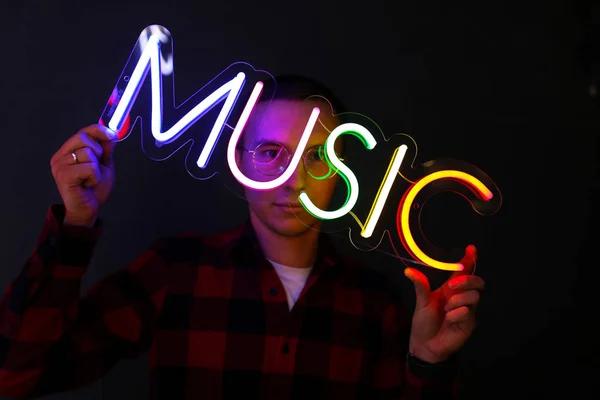 Hipster stilig man vid neon tecken. Flerfärgad neonskylt musik. — Stockfoto