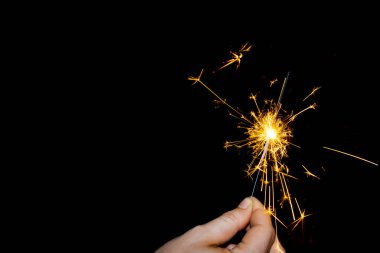 Kıvılcım çıkaran bir kibrit çöpü tutuyor. Siyah arkaplan