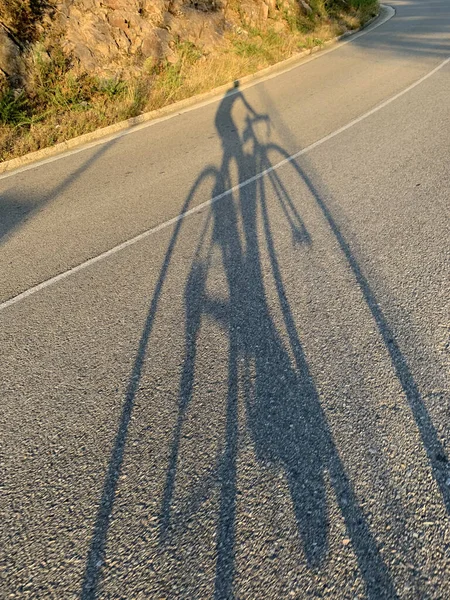骑单车者在爬山路上的影子 — 图库照片