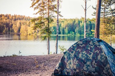 Gölün kıyısında kamp çadırı olan orman manzarası