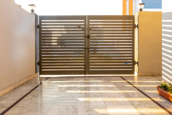 Puertas de entrada de metal gris en una valla de ladrillo con cerradura . Imagen De Stock