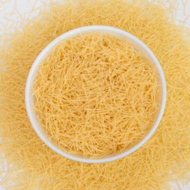 Beyaz arka planda izole edilmiş bir kasede çiğ vermicelli makarna..
