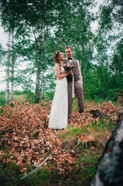 Gelin ve damat yaprakları orman arka plan üzerinde sarılma