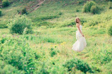 Gelin çimlerin ve dağların arkasında duruyor.