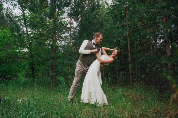 Bruid en bruidegom gek rond op de achtergrond van bladeren bos — Stockfoto