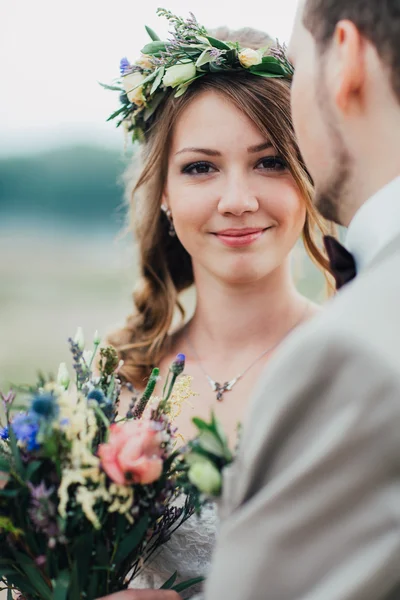 Unga brudgummen och bruden stående kramas på bakgrunden av floden — Stockfoto