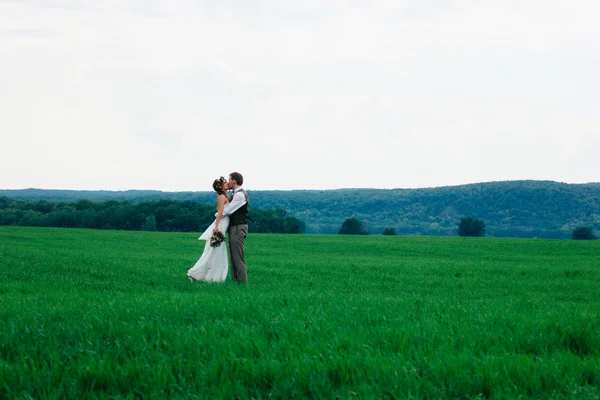 Gli sposi con un bouquet sul campo verde — Foto Stock