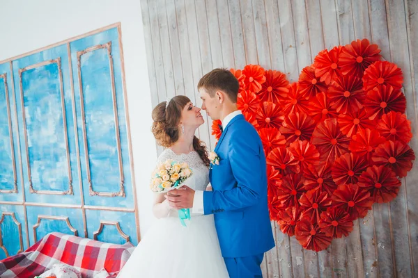 Young groom kissing the bride in a studio interior — Stock Photo, Image