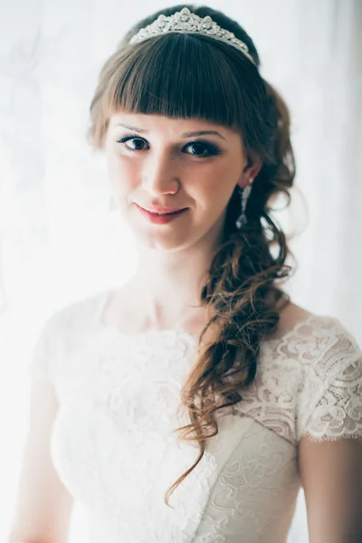 Retrato de uma jovem noiva sorrindo e de pé perto da janela — Fotografia de Stock