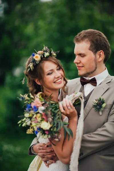 Young happy bride and groom on the background of greenery — Stock Photo, Image