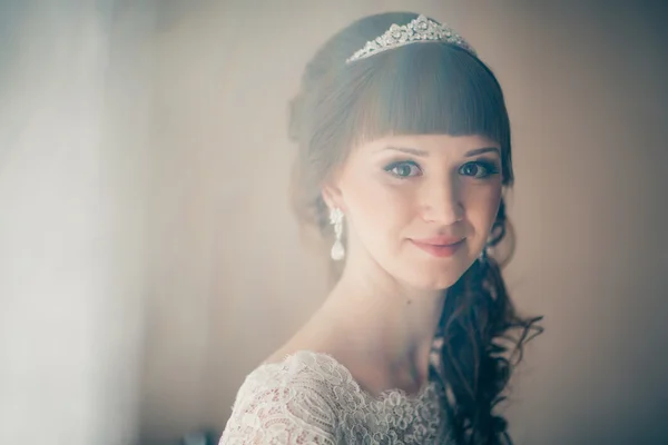 Retrato de uma jovem noiva sorrindo e de pé perto da janela — Fotografia de Stock