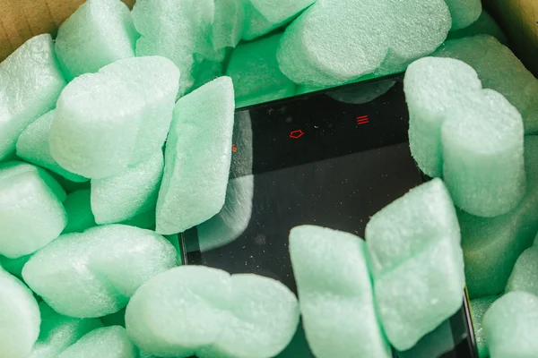 Paquete de tienda en línea, teléfono en una caja de cartón en espuma de poliestireno verde — Foto de Stock