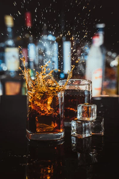 Two glasses of whiskey on a blurred background bar — Stock Photo, Image