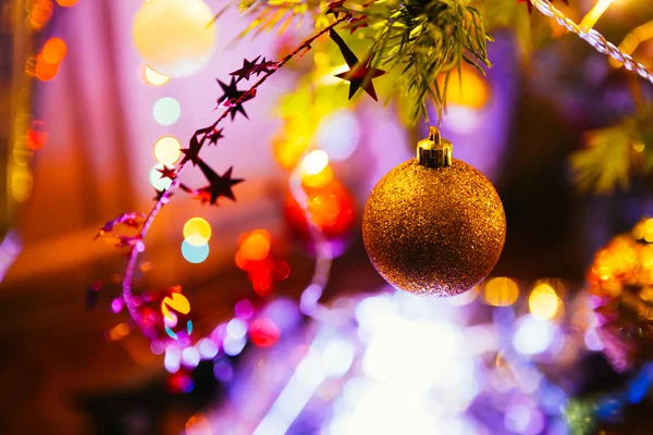 Bola dorada sobre un fondo de ramas verdes de árbol de Navidad —  Fotos de Stock