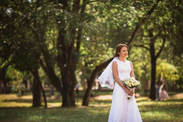 Retrato de uma jovem noiva com buquê de casamento no parque backgro — Fotografia de Stock