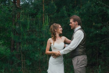 Gelin ve damat arka plandaki ormana sarılıyorlar.