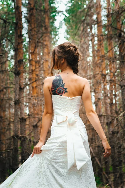 Bride with a tattoo on  background of leaves and forest backlight — Stock Photo, Image