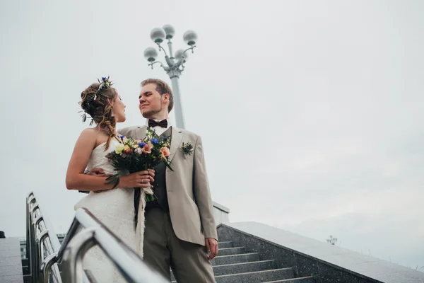 Young bride and groom on the background of the stairs — Stock Photo, Image