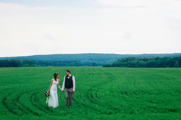 La mariée et le marié avec un bouquet sur le champ vert — Photo