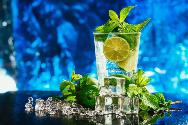 Glass of mojito with lime and mint ice cube close-up red straw on blue background — Stock Photo, Image