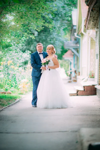 Bride and groom on the background of the garden fence — Stock Photo, Image