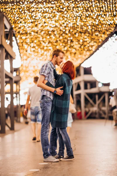 Joyeux couple embrassant le soir sur des guirlandes légères — Photo