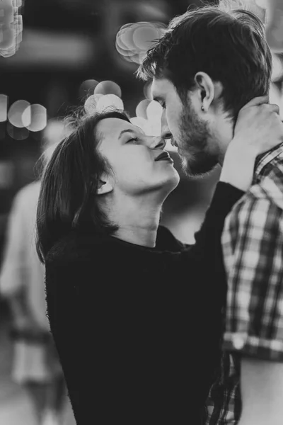 Foto em preto e branco de um casal feliz abraçando beijos à noite em guirlandas leves — Fotografia de Stock