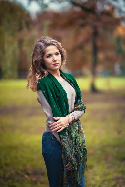 Ritratto di giovane ragazza con sciarpa verde sullo sfondo del parco autunnale — Foto Stock