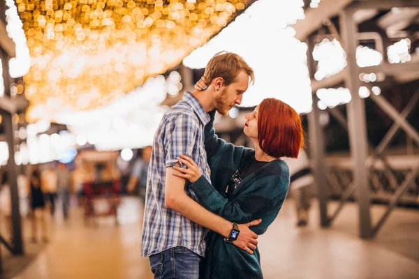 Casal feliz abraçando de tarde em umas grinaldas leves — Fotografia de Stock