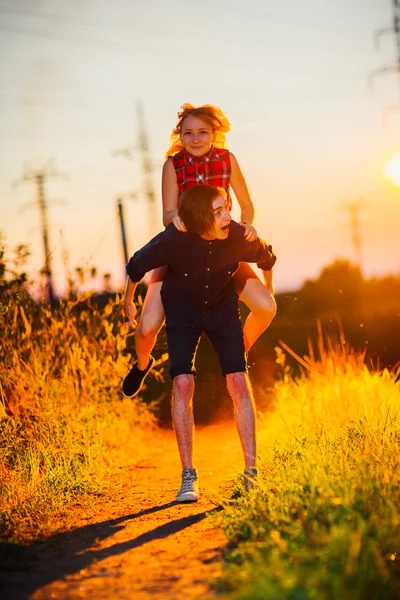 Jongen en het meisje staan zoenen in de zonsondergang achtergrond — Stockfoto