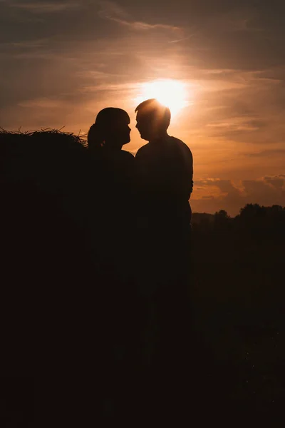 Silhuetas de homem e mulher em um contexto o campo de sol — Fotografia de Stock