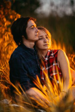 adam ve çim günbatımı bir arka plan üzerinde oturan kız