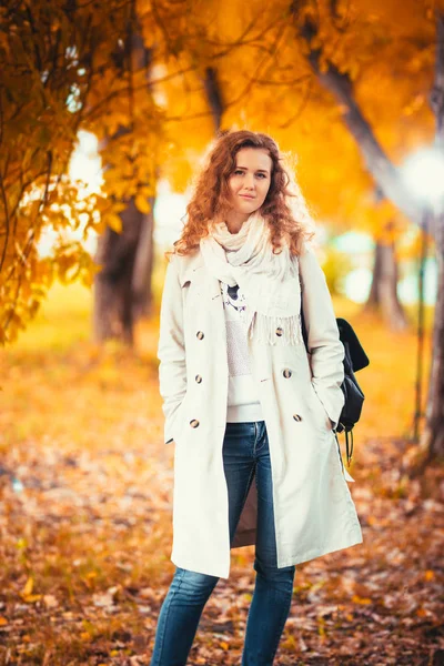 Menina em um casaco leve no fundo do parque de outono — Fotografia de Stock
