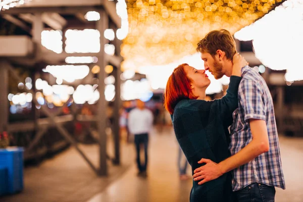 Lyckligt par omfamnar och kysser på kvällen på en ljus kransar — Stockfoto