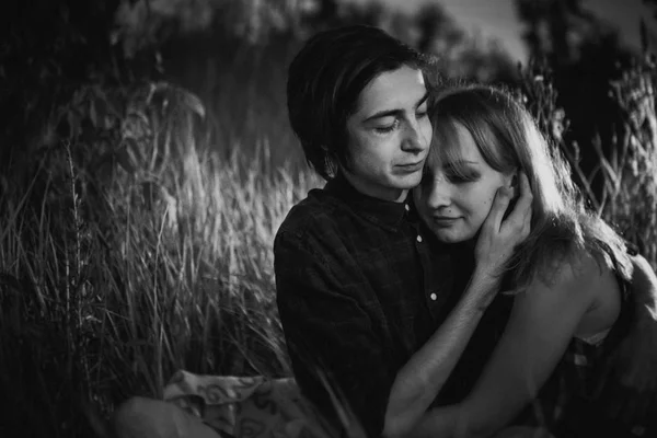 Black and white guy the girl sitting in the grass on a sunset background — Stock Photo, Image