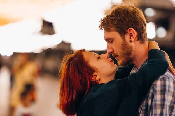 Casal feliz abraçando e beijando à noite em uma grinalda leve — Fotografia de Stock