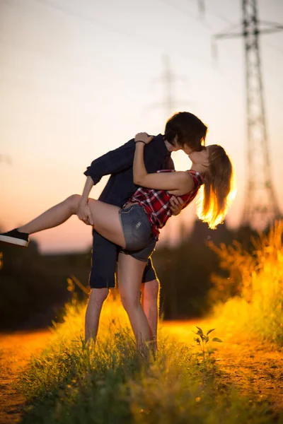 Mann und Mädchen stehen küssend im Hintergrund des Sonnenuntergangs — Stockfoto