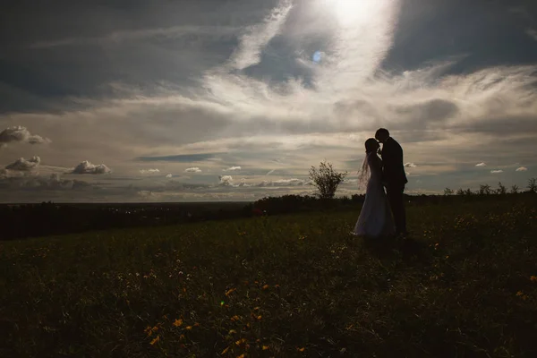 Silhouetten von Braut und Bräutigam am Feldhimmel im Hintergrund — Stockfoto