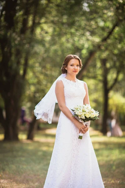 Genç gelin düğün buket üzerinde park backgro ile portresi — Stok fotoğraf